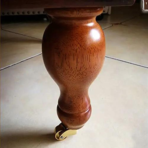 Pro Level Solid Brass Swivel Castor Wheels Set Of Four Featuring Tough As Nails Iron Cores And Slick Antique Gold Finish mounted on a wooden leg.