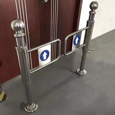 Built Solid Stainless Steel One Way Swing Gate Spring Loaded Auto Closing Security Door No Nonsense Traffic Flow For Busy Retail Shops And Industrial Warehouses, showing a polished stainless steel gate with directional arrows.