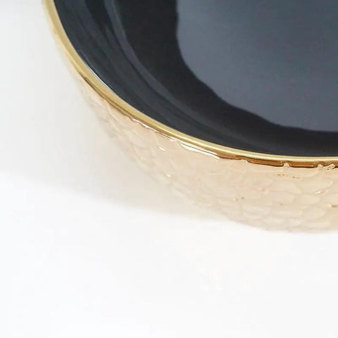 Close-up of a USZWBY Vessel Sinks Ceramic Vessel Sink with a sleek black bowl and textured gold rim for modern bathrooms.
