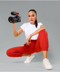 Top Shelf Compact Shotgun Camera Microphone Bundle With Lightning Cable Tabletop Tripod Stand And Handheld Grip held by a woman in red pants.