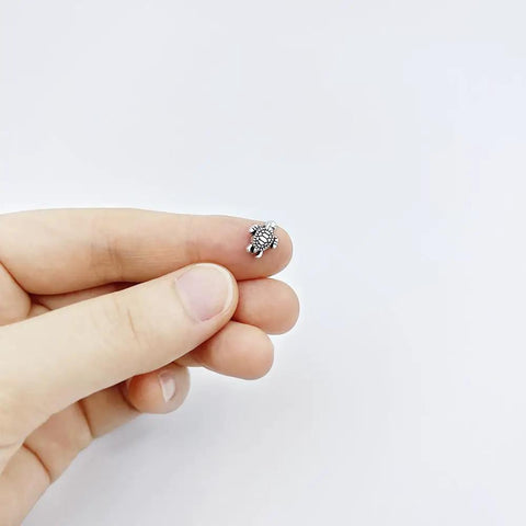 Hand holding a tiny antique silver turtle bead 0.9x0.7cm for crafts from 100 Pcs Dope Tiny Turtle Beads Antique Silver 0.9x0.7cm set