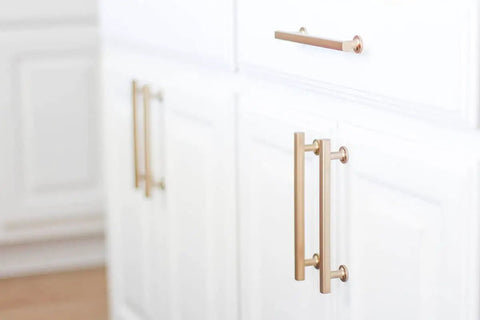 Gold kitchen cabinet handles on white cabinetry, contrasting other hardware. Featuring Freestone Appliance Pull From Urban Modern Collection, 12 Inch Center To Center, Flat Black Coated Finish, Dope Kitchen Cabinet Hardware Upgrade, Durable Solid Brass Construction, Model 87001.