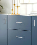 Close-up of polished chrome T bar cabinet pulls 256mm hole centers 10 inch center to center on blue kitchen cabinets