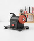Compact Bench Top Grinder With Rock Solid Base Dual Sharpening Wheels on a workbench, showcasing white and red grinding wheels.