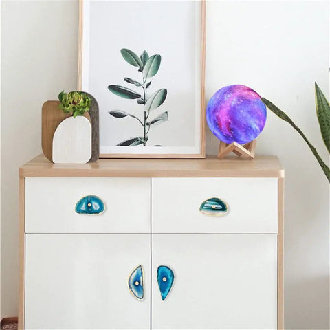 Super Chic Agate Stone Cabinet Knobs With Gold Plated Edges on a white dresser, showcasing textured blue gemstone design.