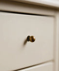 Built Like A Tank Solid Zinc Alloy Cabinet Knobs 10 Pack Antique Brass single hole ball knob on white drawer.
