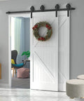 Heavy Duty Sliding Barn Door Hardware Kit Double Track System With Smooth Ride Rollers And Drop Dead Simple Install Bent Hangers In Slick Black Finish bedroom room divider shown with a white door and wreath.