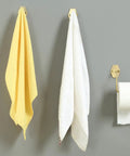 Top Shelf Brass Wall Hooks For Towels And Mugs No Sweat Rust Proof Bathroom Hanger holding yellow and white towels on a gray wall.