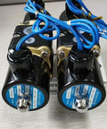 Badass Four Way Brass Solenoid Valve For Smooth Air Ride Suspension Control With Dual Station Manifold And Half Inch NPT Fittings For Zero Hassle Inflate And Deflate Response On DC12V Systems close-up of two solenoids with blue wiring on a mounting plate.