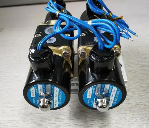 Badass Four Way Brass Solenoid Valve For Smooth Air Ride Suspension Control With Dual Station Manifold And Half Inch NPT Fittings For Zero Hassle Inflate And Deflate Response On DC12V Systems close-up of two solenoids with blue wiring on a mounting plate.