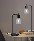 Table lamps with clear seeded glass shades on a desk featuring modern design, displaying focused light effect.