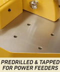 Close-up of Heavy Duty 5 HP Spindle Shaper With Cast Iron Base showing predrilled holes for power feeders on metal table.