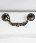 Straight Up Vintage Antique Bronze Drop Bail Pulls With Slick Carved Texture Top Shelf Cabinet Handles For Drawers And Closets Featuring 3.8 Inch Hole Centers, viewed from above on white drawer.