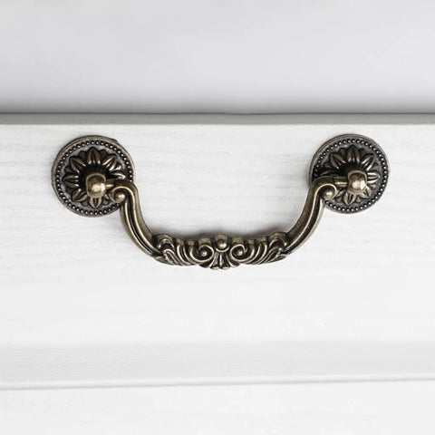 Straight Up Vintage Antique Bronze Drop Bail Pulls With Slick Carved Texture Top Shelf Cabinet Handles For Drawers And Closets Featuring 3.8 Inch Hole Centers, viewed from above on white drawer.