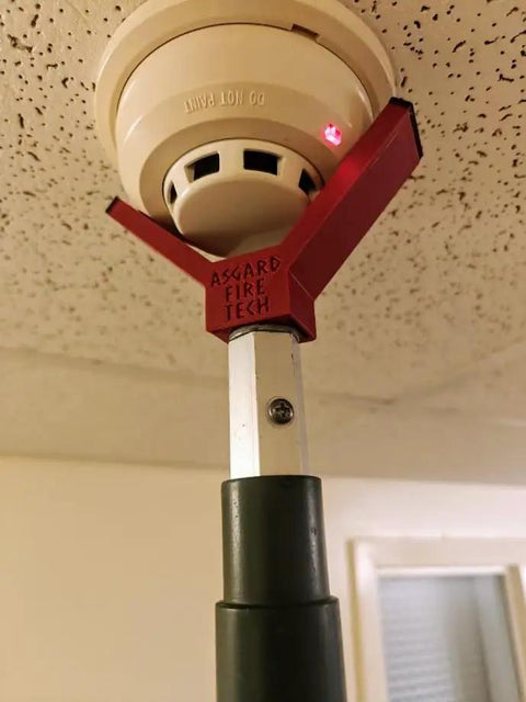 Rock Solid Dual Magnet Smoke Detector Test Tool For Fire Safety Systems With Quick Pole Thread Adapter and Duct Activation Features mounted on a smoke alarm.