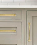 Close-up of polished brass drawer handles installed on gray kitchen cabinets, showcasing the 10 Pack 10 Inch Center To Center Cabinet Pulls Rock Solid Heavy Duty Polished Brass Drawer Handles No Nonsense Build For Kitchen Cabinets Dressers And Bathroom Remodels Killer Shine Finish.