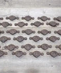25 Pack Rock Solid Cast Iron Cup Handles In Rich Brown For Drawers And Cabinets With Ornate Rustic Vintage Charm arranged on wood.