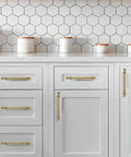 10 Pack 3 1/2 Inch Hole Center Brushed Brass Cabinet Pulls on white kitchen cabinetry with hexagonal backsplash.