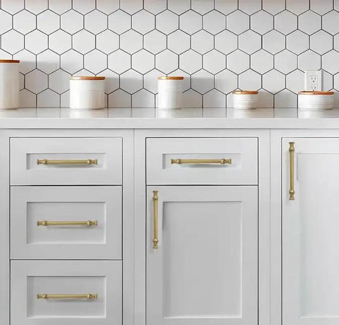10 Pack 3 1/2 Inch Hole Center Brushed Brass Cabinet Pulls on white kitchen cabinetry with hexagonal backsplash.
