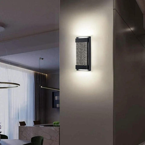 Glass Bubble LED Wall Sconce for indoor outdoor use with matte black finish and essence bubble glass, mounted on wall in living space.