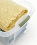 Rock Solid 95 Quart Clear Plastic Storage Bin With Easy Grip Handles For No Sweat Organization And Smooth Transport Legit Extra Large Bulk Storage Container holding yellow and green blankets.