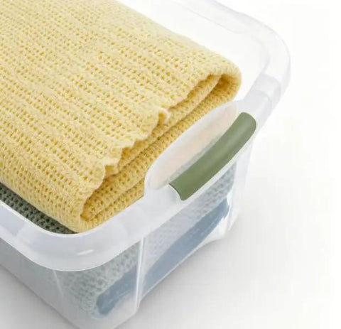 Rock Solid 95 Quart Clear Plastic Storage Bin With Easy Grip Handles For No Sweat Organization And Smooth Transport Legit Extra Large Bulk Storage Container holding yellow and green blankets.