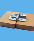 180-degree positioning hinge, silver alloy; close-up view on wooden blocks used for cabinet/table hinge.