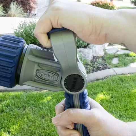 Heavy Duty Seven Pattern Firemans Hose Nozzle With Adjustable Pressure Rust Proof Yard Sprayer Tough As Nails For Garden Cleanup And Flushes Every Job Real Slick Like A Champ, hand gripping nozzle outdoors.