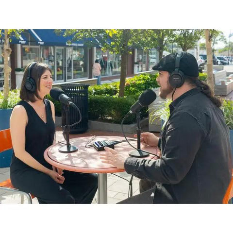Two hosts recording a podcast outdoors with dynamic mics and headphones for The Ultimate Two Host Podcast Stack Featuring Multitrack Recorder And Dynamic Mics Paired With Headphones Shielded Xlr Cables Tripod Stands And Foam Windscreens For Streaming That Sounds Gnarly And Helps You Drop Bangers On Daily Grind.