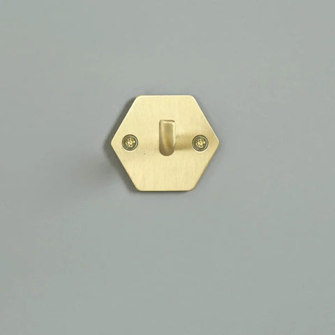 Top Shelf Brass Wall Hooks For Towels And Mugs No Sweat Rust Proof Bathroom Hanger on a grey wall, hexagonal design.