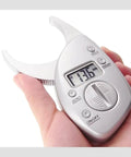 Pinch And Read Digital Body Fat Caliper With LCD Display held in hand, showing measurement in millimeters on screen.