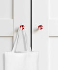 Premium 2 Piece Christmas Cabinet Knobs And Drawer Pulls Featuring A 1.4 Inch Round Design With A Killer Red Abstract Gradient Finish Crafted From Smooth Solid Beech Wood For Sweet Home Renovations on white cabinet with tote bag.