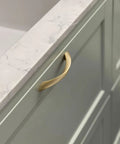 Top Notch 5 Inch Arch Cabinet Pulls Featuring Brushed Gold Zinc Alloy Build on a green cabinet with a marble countertop.