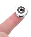 Solid Pack Of Ten Drop Dead Tight V Groove Ball Bearings 4X18X8MM Track Rollers on a finger showing size and design.