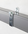 Close-up of a 44-inch door barricade bar with folding brackets installed with hardened screws on a wall.