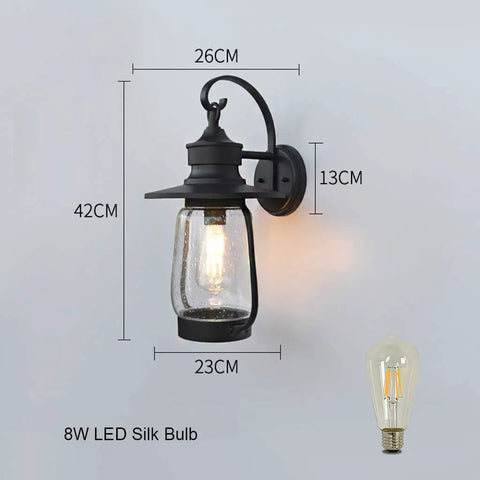 Rock Solid Outdoor Wall Lantern With Slick Industrial Design And Transparent Bubble Glass Shade Featuring A Top Shelf Led Filament Bulb, measures 42cm by 26cm.