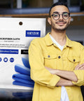 Front view of 20-pack blue microfiber glasses cleaning cloths in packaging beside a man wearing a yellow jacket