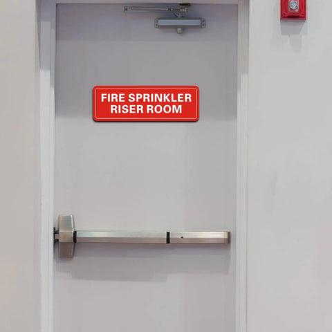 Hella Durable Fire Sprinkler Riser Room Sign Two Pack Self Adhesive Aluminum Warning Tag For Home Garage Or Business Reflective Weatherproof Fade Resistant 9X3 Inch Safety Label on a door.