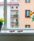 High Load Stainless Steel Sliding Glass Door Rollers Four Pack Double Wheel Track Glides on a windowsill next to potted plants.