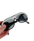 Killer Welding Safety Glasses With Dang Tough Scratch Proof Lens And Boss Level Spark Shield featuring black and white design, held by hand.
