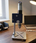 Compact Mini Desktop Drill Press For Home Workshop on wooden table with heavy base and precision drill head for DIY projects.