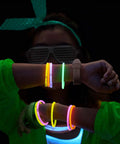 Person wearing 100 Count Glow Sticks Bulk Party Pack with 8 Inch Glow Bracelets and Connectors in assorted colors, glowing in the dark.