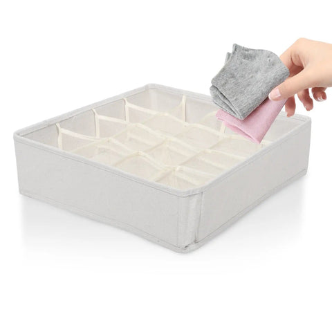 Hand placing rolled socks into Super Slick 16 Compartment Foldable Drawer Storage Box For Underwear And Socks Made From Soft Cotton Linen Blend In Warm Beige.