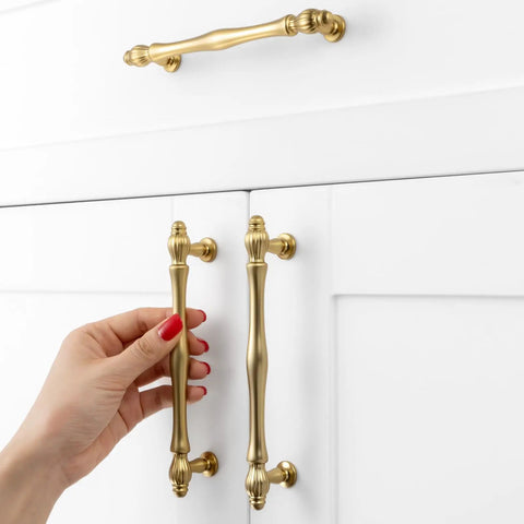 Rad Five Inch Brushed Gold Cabinet Pulls And Drawer Handles with hand installing on white cabinet doors.