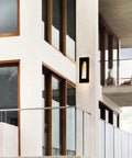 Heavy Duty Two Light Outdoor Wall Lantern In Sleek Modern Style With Top Shelf Solid Aluminum Frame And Rich Bronze Coating For Hella Bright Led Glow Measuring Nine By Twenty Four Inches mounted on a modern home exterior.