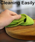 Hand wiping the Smooth As Butter 14 Inch Solid Acacia Wood Lazy Susan Rotating Turntable for easy cleaning.