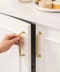 Hand pulling open a cabinet with 10 Pack 5 Inch Brushed Brass Cabinet Pulls Solid Zinc Alloy Heavy Duty Kitchen And Bathroom Drawer Handles Tough As Nails For Home Improvement And Renovations.