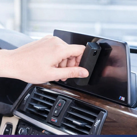 Hand using 2 Pack Car And Device Screen Cleaner Spray And Wipe 2 In 1 Touchscreen Mist Cleaner For iPhone iPad Laptop MacBook And More With Microfiber Cloth Streak Free Fingerprint Remover Grey And Rose Gold on car display.