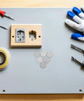 10 Pack Round Stainless Steel Knockout Plugs For Junction Boxes And Electrical Panels on a workshop table with tools.