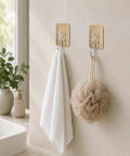 Six Pack Tough Grip Adhesive Wall Hooks Offering No Sweat No Drill Install Slick Gold Square Plate And Clear Hooks holding white towel and beige loofah.
